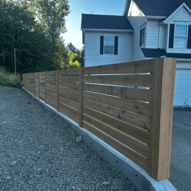 Horizontal cedar slat fence installation on concrete retaining wall in Wilsonville OR – Oregon Quality Cuts